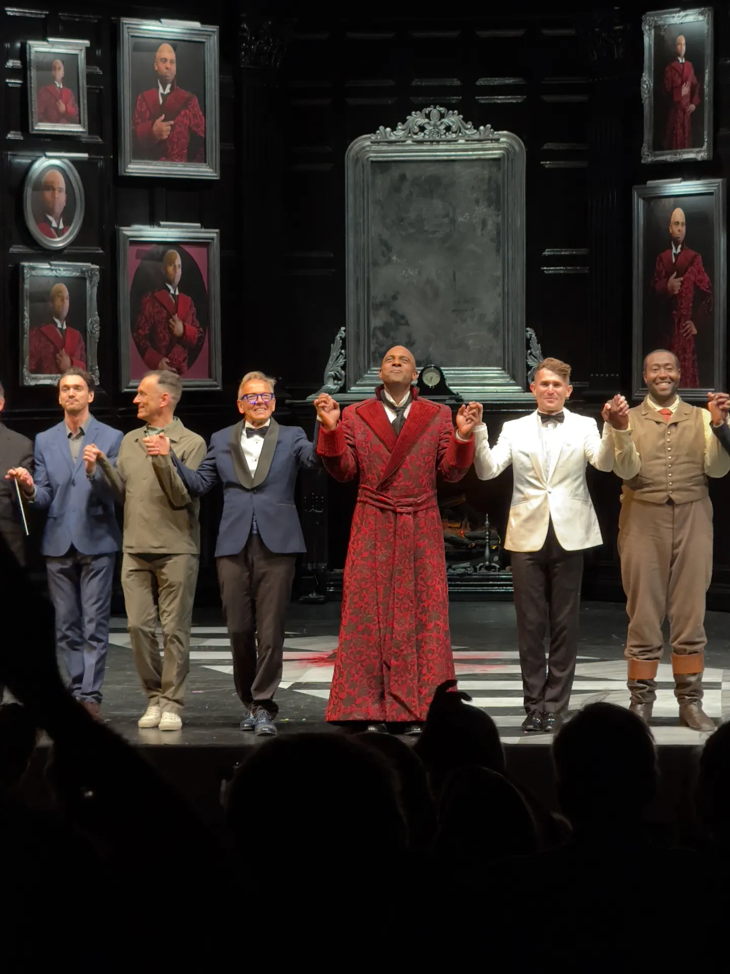 Principals of The Picture of Dorian Gray at curtain call, the title character center in red brocade dressing gown, surrounded by portraits of himself