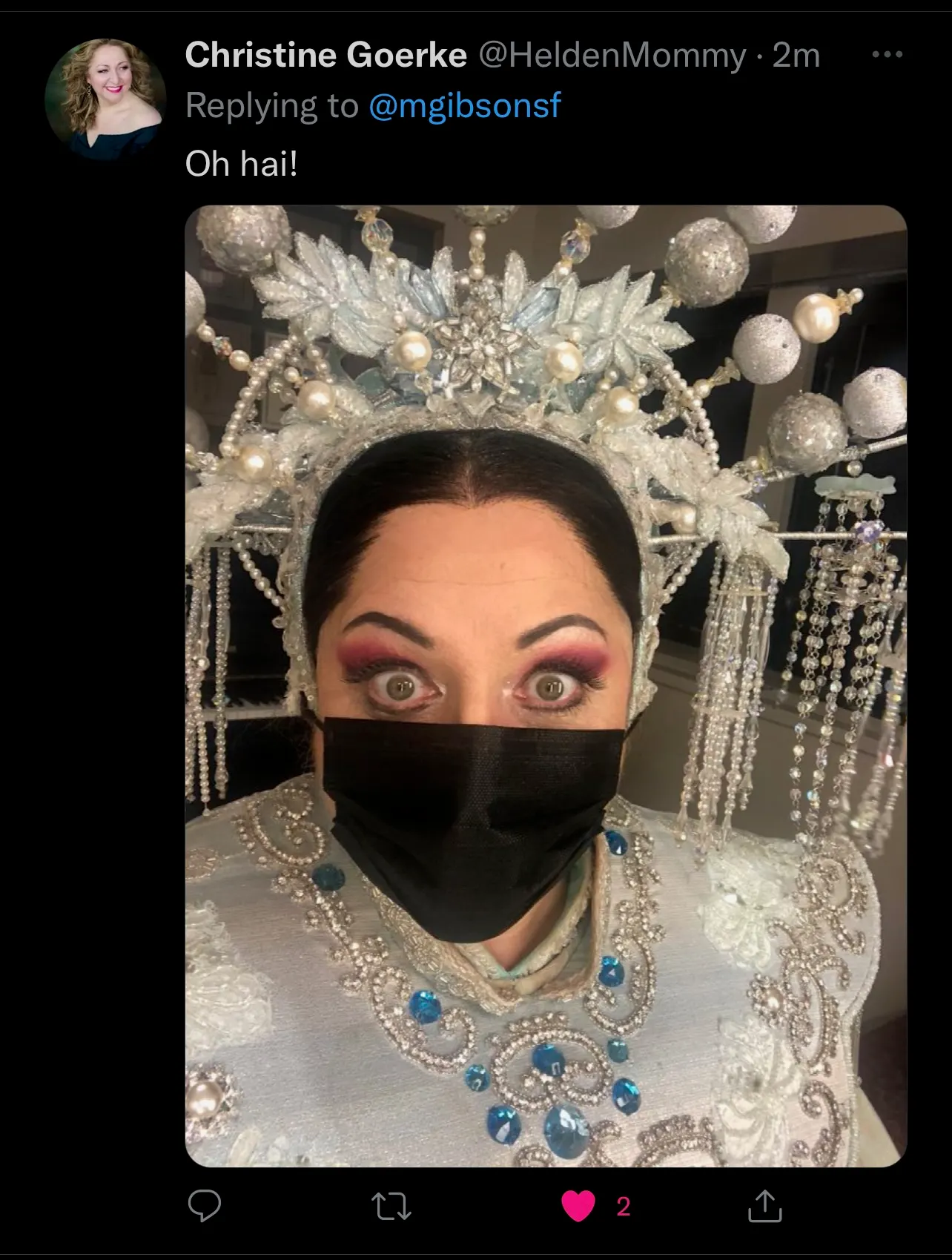 Tweet from soprano Christine Goerke in full Turandot crown and costume wearing a black surgical mask, replying 'Oh hai!'