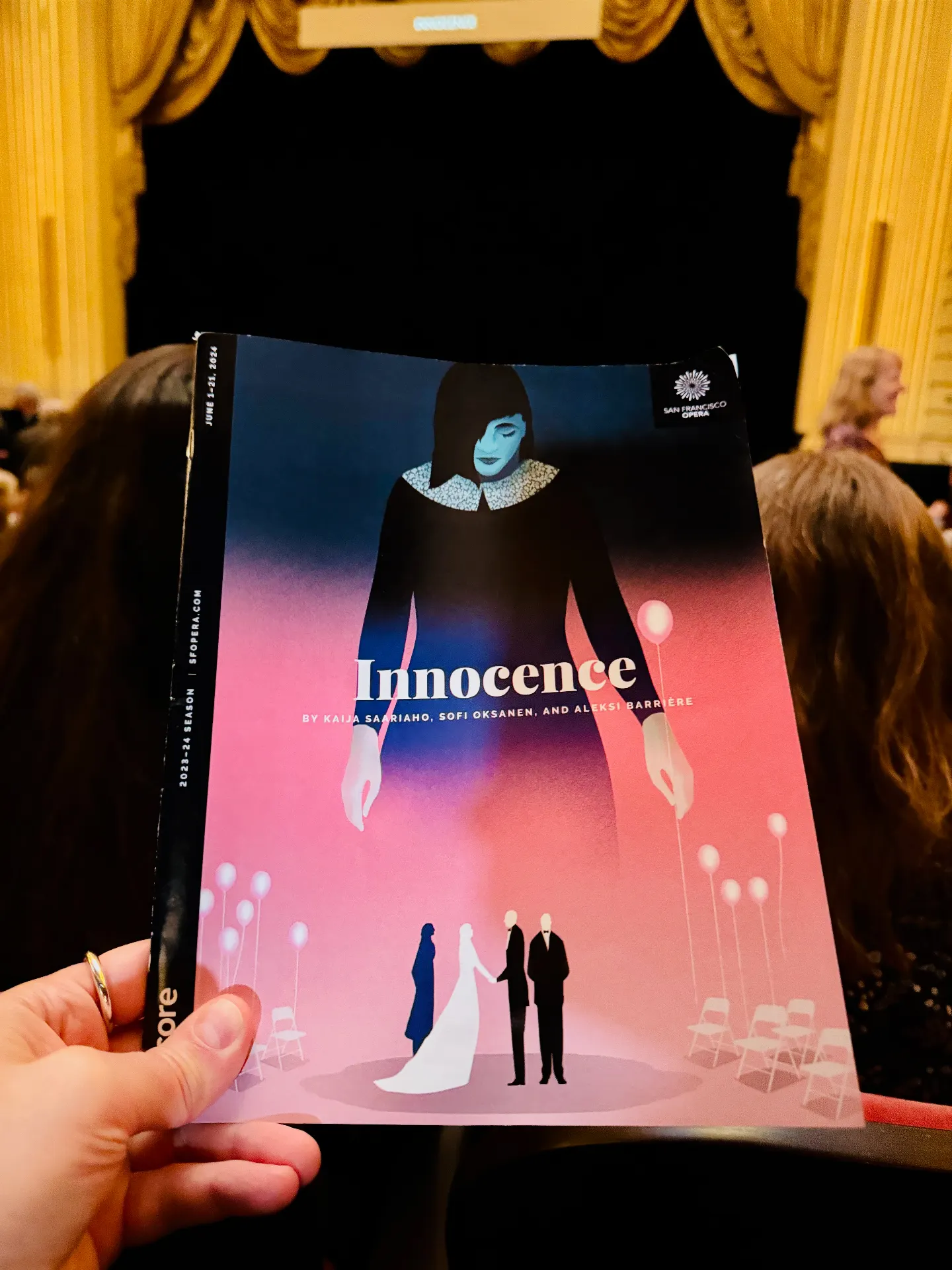 Innocence program held up in front of the gilded SF Opera proscenium before the show begins