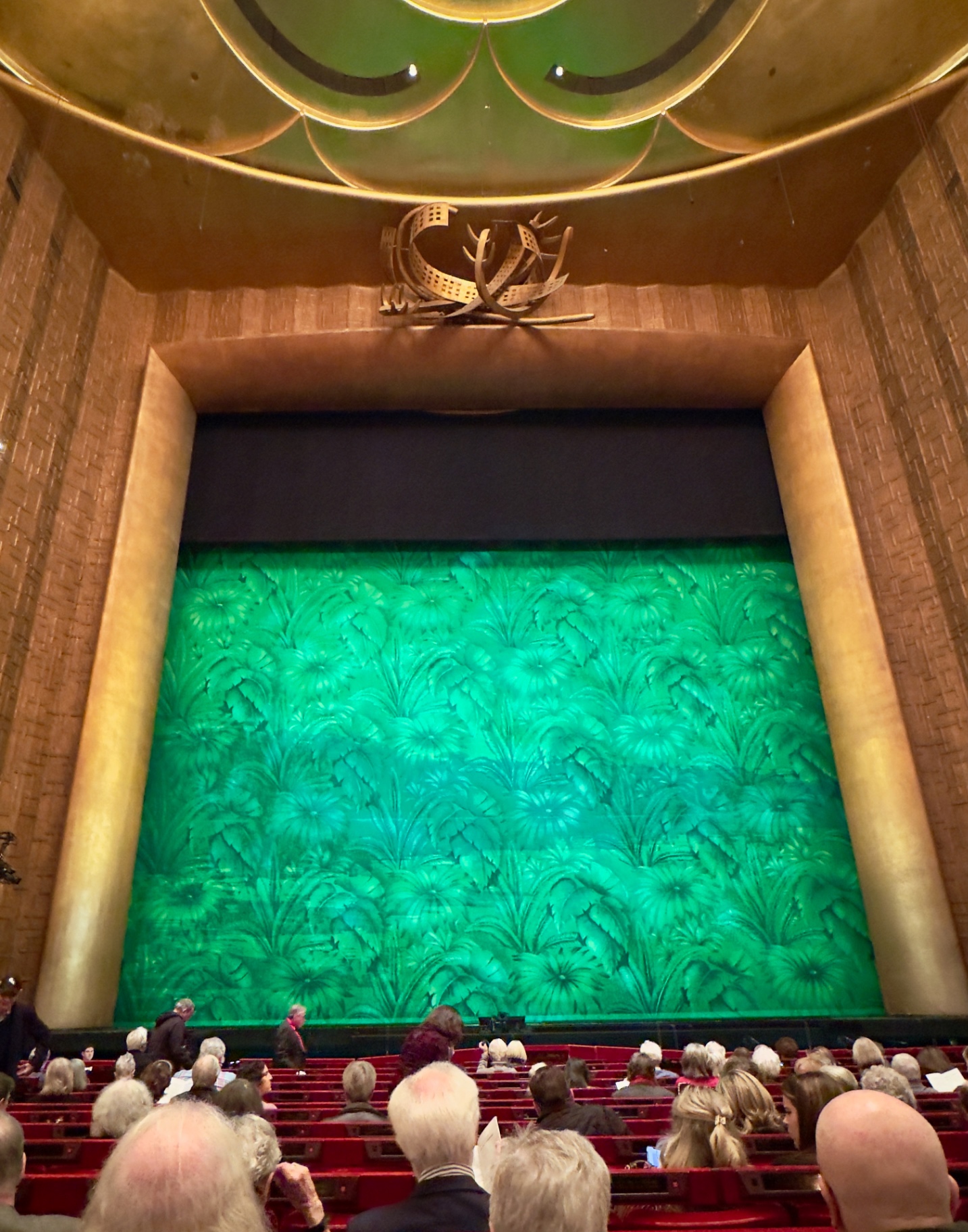 Green floral show curtain for Florencia en el Amazonas at the Met, gold proscenium and antlered chandelier above