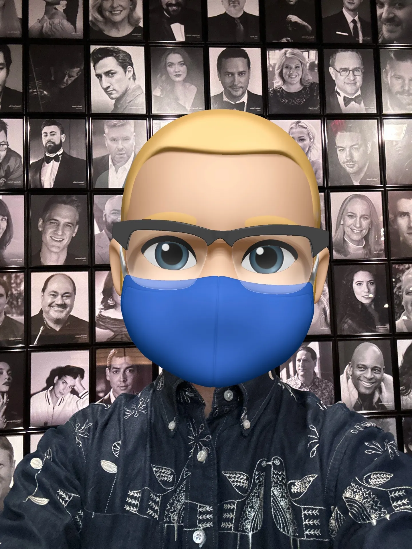 Memoji selfie in a blue mask in front of the Metropolitan Opera's wall of black-and-white artist portraits