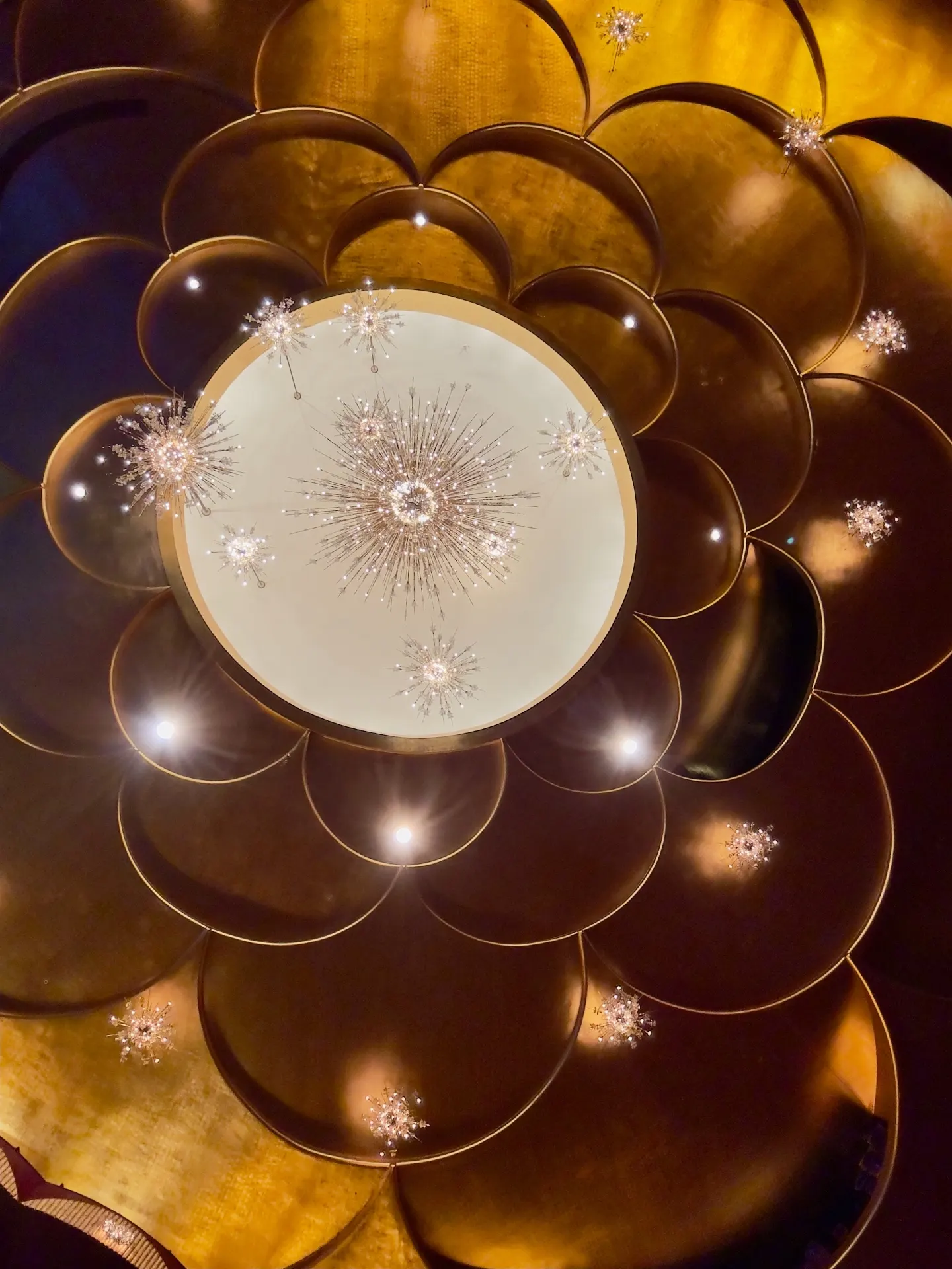 Looking straight up at the Metropolitan Opera lobby ceiling, gold leaf scalloped coffers framing the Sputnik chandelier