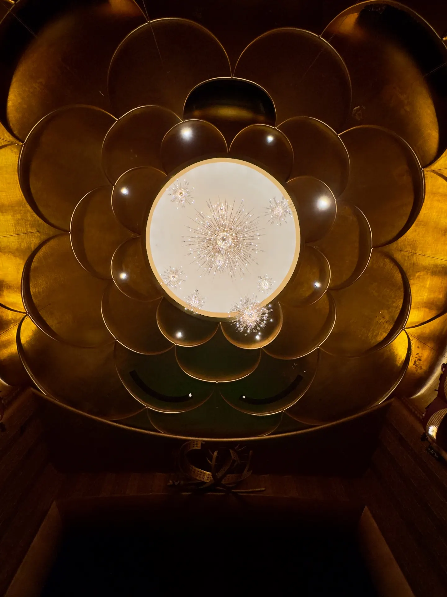Looking straight up into the Met's gilded scalloped dome, central oculus with the starburst Sputnik chandelier suspended in it