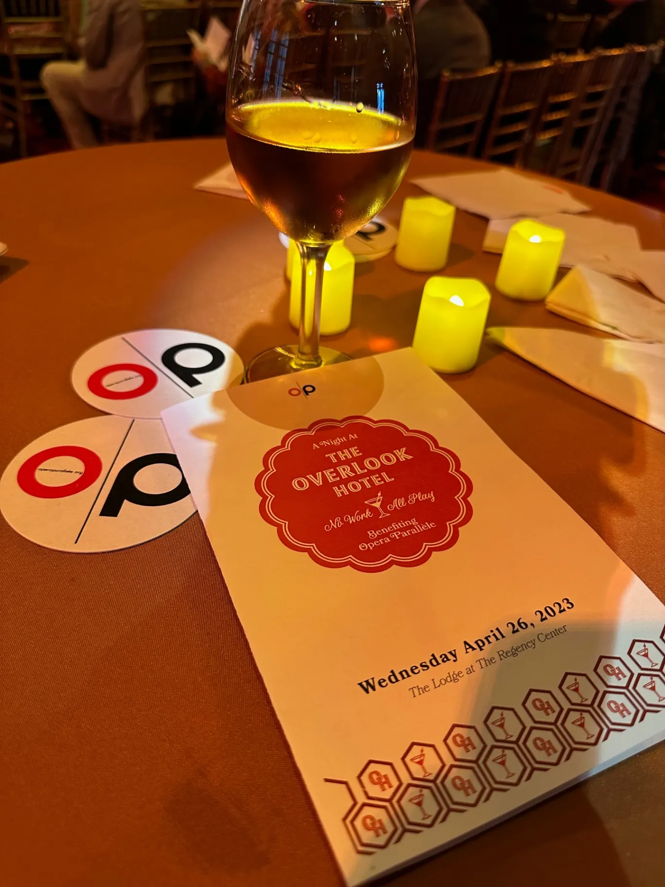 Opera Parallèle gala table at the Regency Center — wine glass, votives, and a program for 'A Night at The Overlook Hotel'