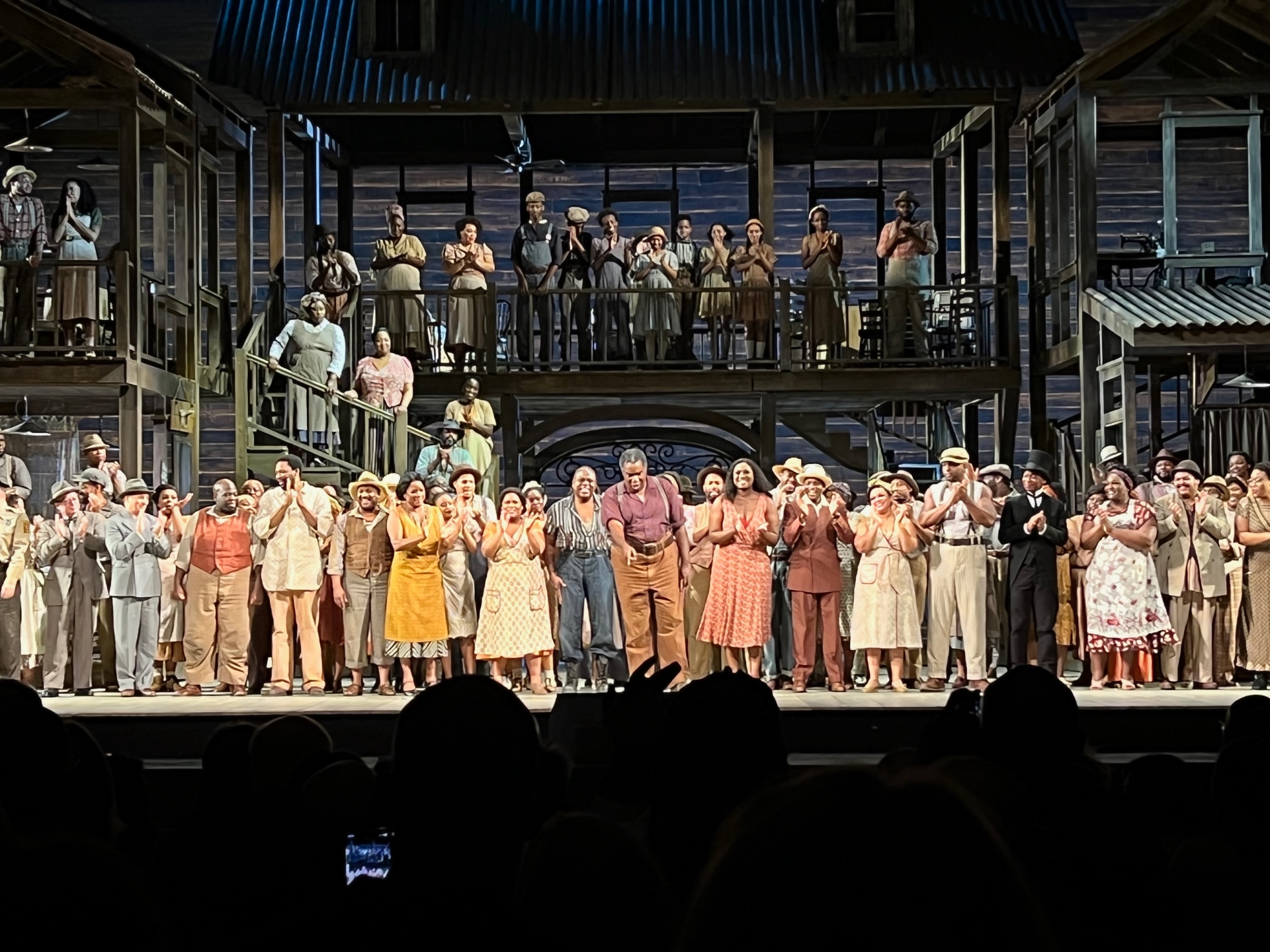 Curtain call of Porgy and Bess with a large ensemble cast on a two-story Catfish Row set